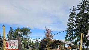 Un letrero de motel, un área de estar cubierta al aire libre y un jardín ajardinado con diversas plantas.