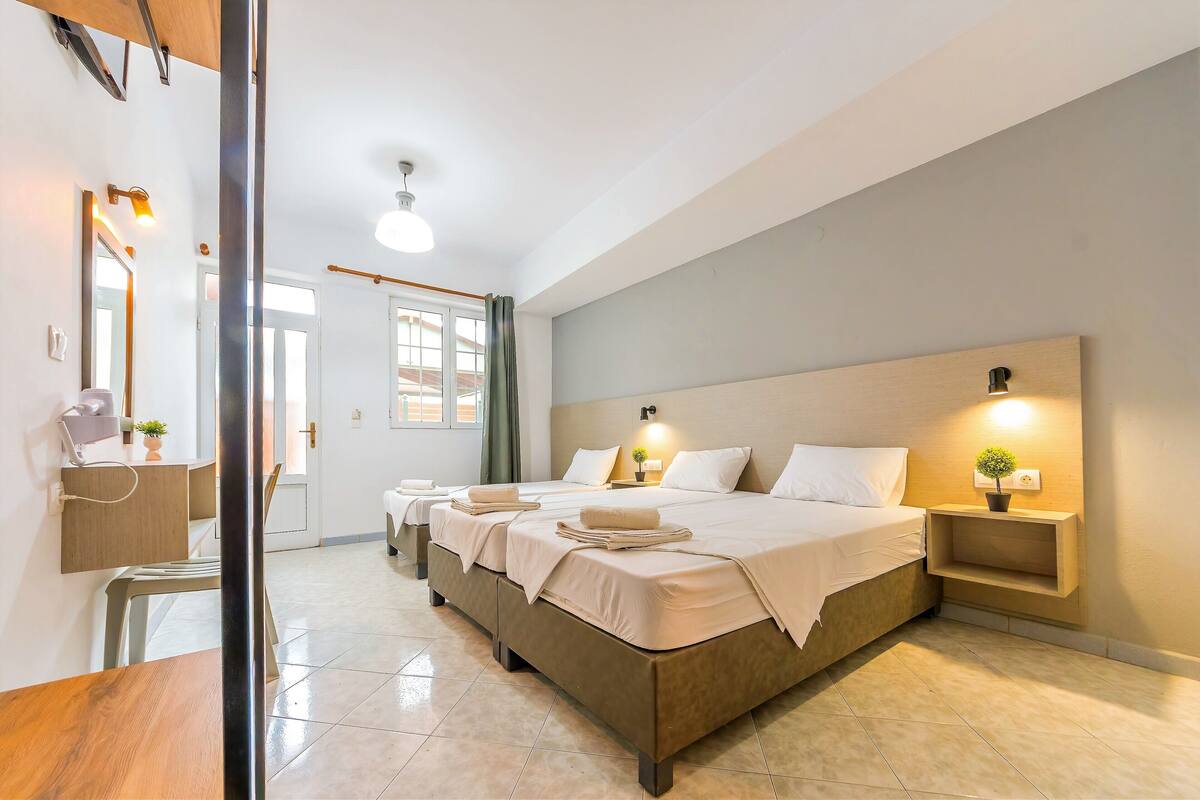 A hotel room with a large bed, bedside tables with lamps, a mirror, and a view of the outside.