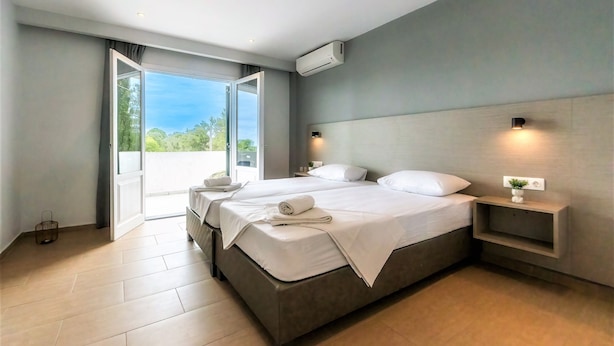 Una habitación de hotel moderna con una cama grande, una mesita de noche y un equipo de aire acondicionado.