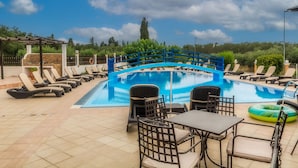 Un área de piscina con sillas de descanso, una mesa y una valla azul.