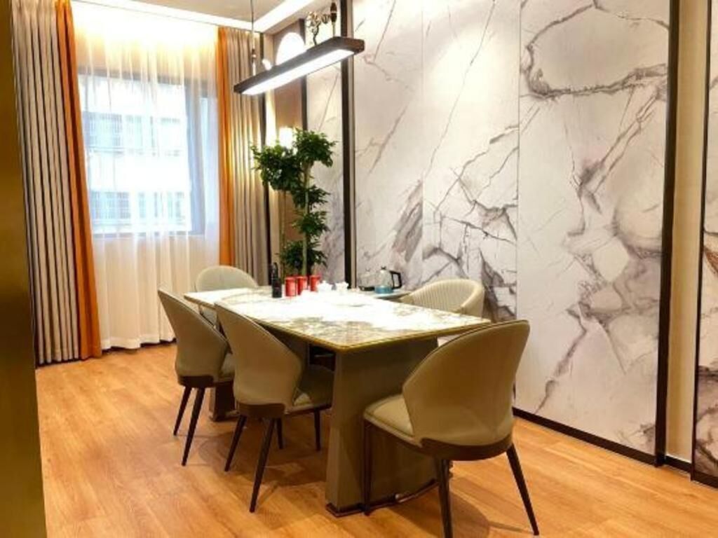 A dining area with a marble wall, a table with chairs, and a plant.