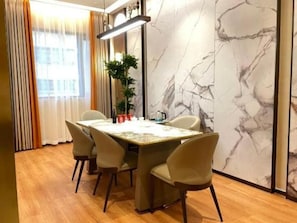 A dining area with a marble wall, a table with chairs, and a plant. - Chaozhou Hotel (CHAOZHOU)