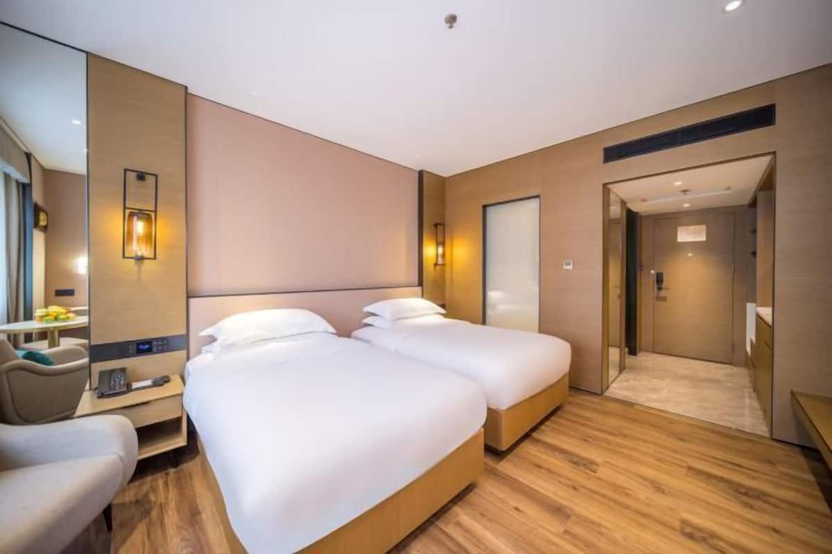 A hotel room with two beds, a desk, a chair, and a walk-in closet.