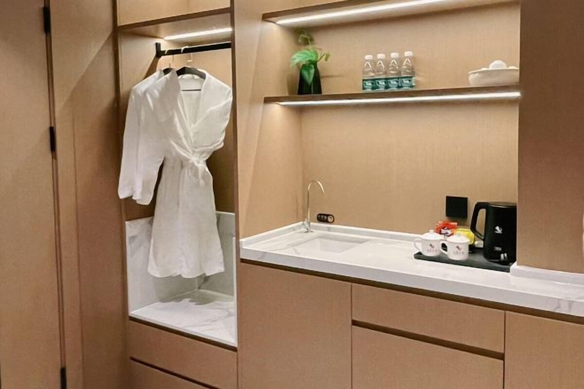 A bathroom with a sink, a robe hanging on a rack, and toiletries on a shelf.