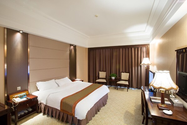 A hotel room with a large bed, a desk with a lamp, a chair, and a television. - Chaozhou Hotel (CHAOZHOU)