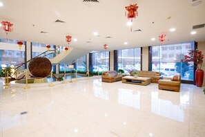 A spacious lobby with a central staircase, comfortable seating areas, and large windows offering views of the outside. - Chaozhou Hotel (CHAOZHOU)