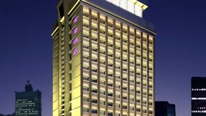 A high-rise hotel with a grid of illuminated windows, a prominent vertical sign with text, and a modern architectural design. - Dreamland Hotel Huizhou (Huizhou)