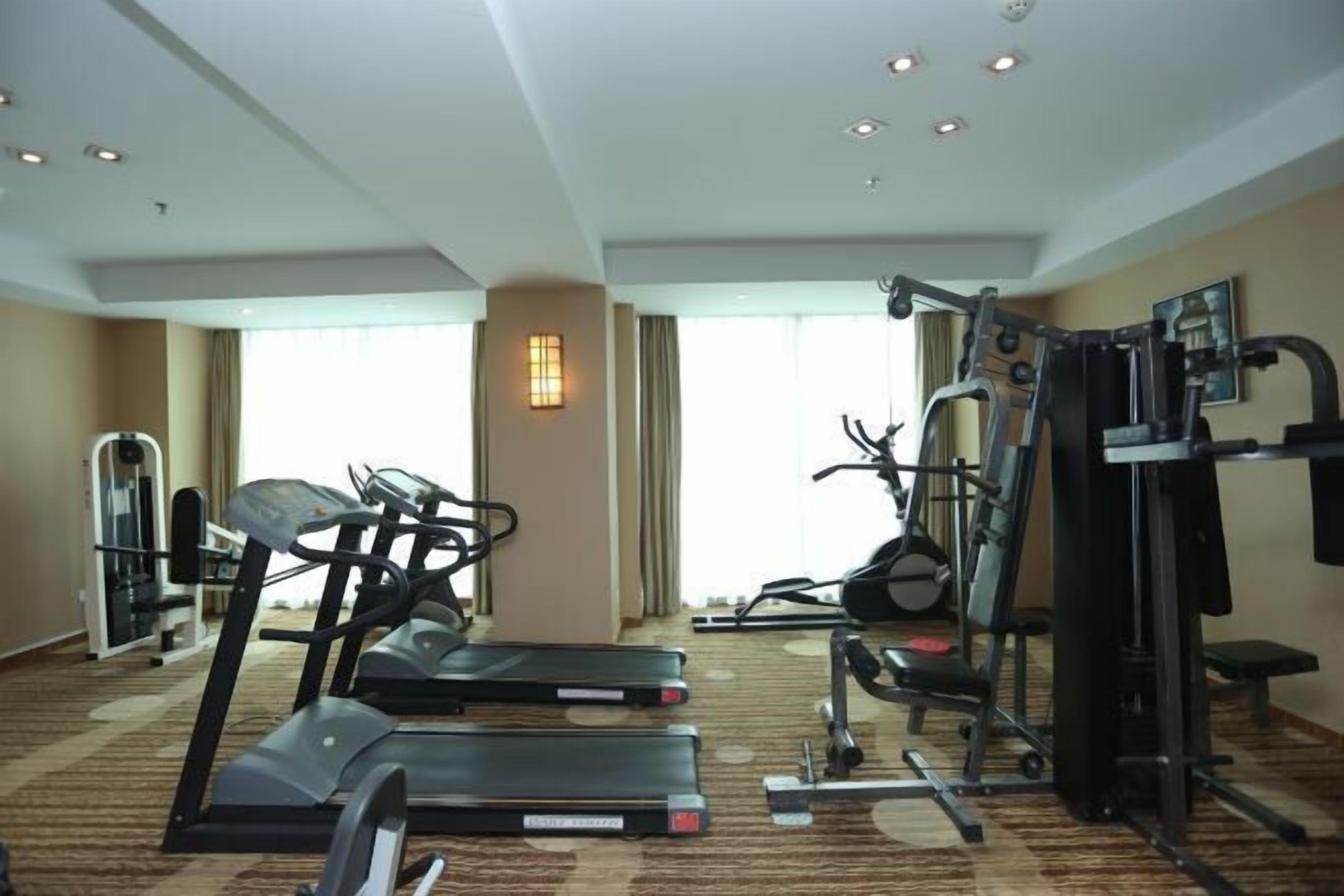 A hotel fitness room with treadmills, a weight machine, and a mirror.
