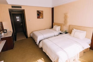 Una habitación de hotel con dos camas, un escritorio y una puerta que da a un baño.