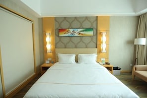 Habitación de hotel con una cama grande, dos mesitas de noche, una lámpara y un cuadro en la pared.