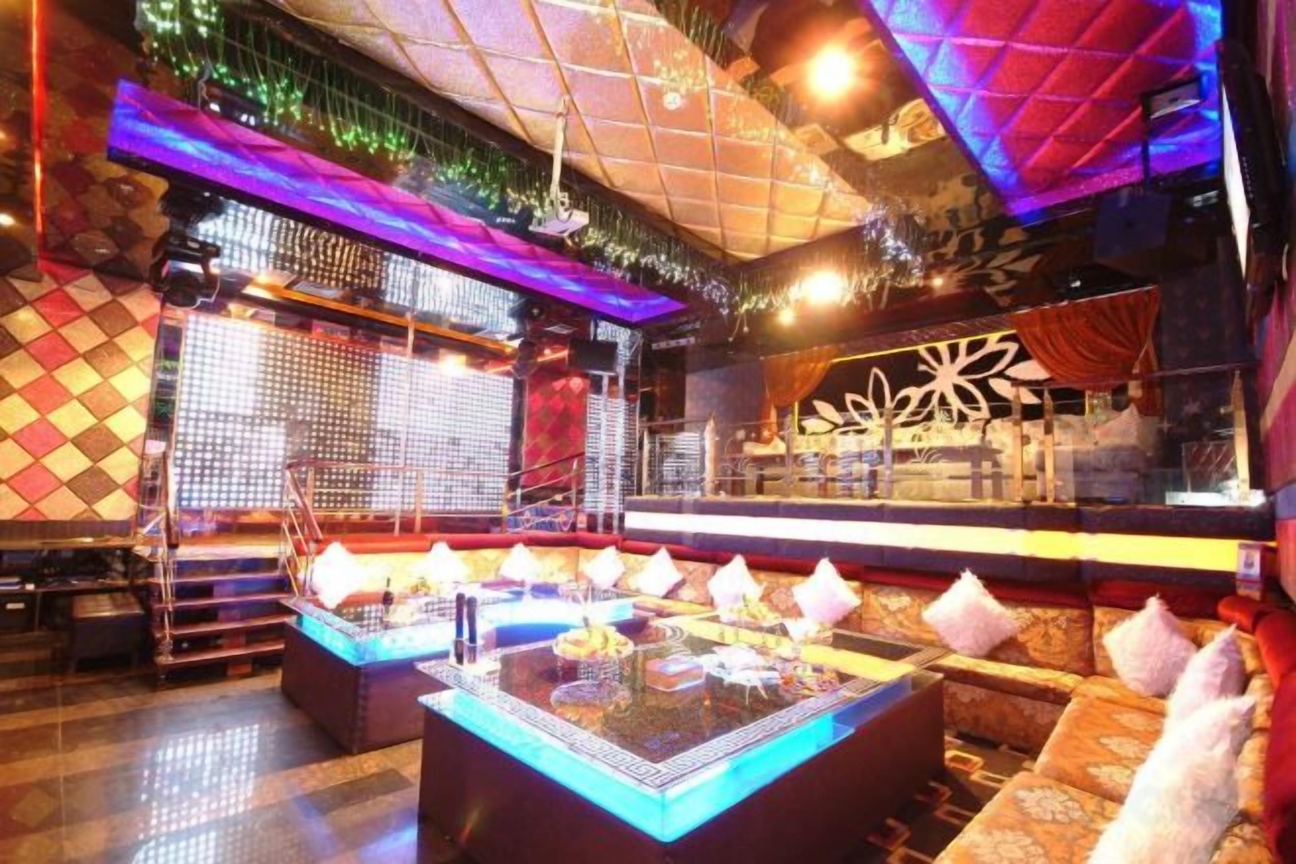 Una zona de bar con mesa de billar, asientos acolchados y una pared decorativa.