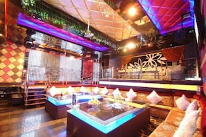 Una zona de bar con mesa de billar, asientos acolchados y una pared decorativa.