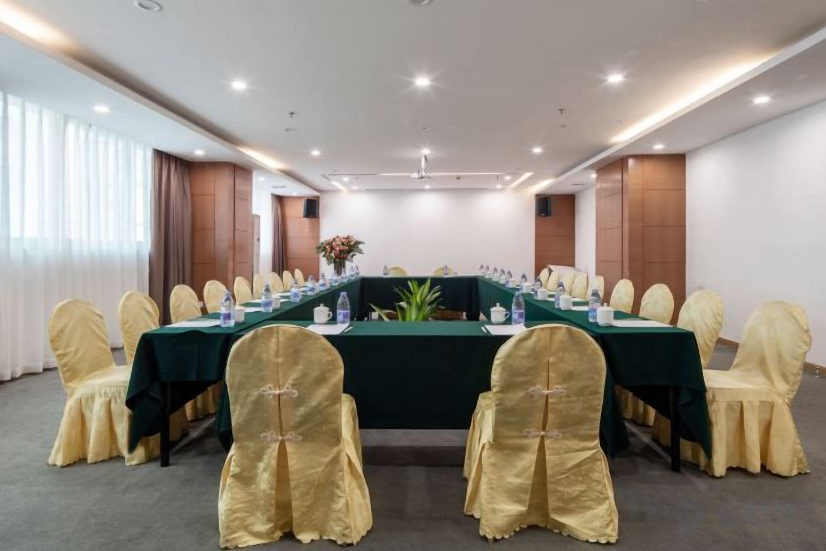 Una sala de conferencias con una larga mesa, sillas y un arreglo floral.