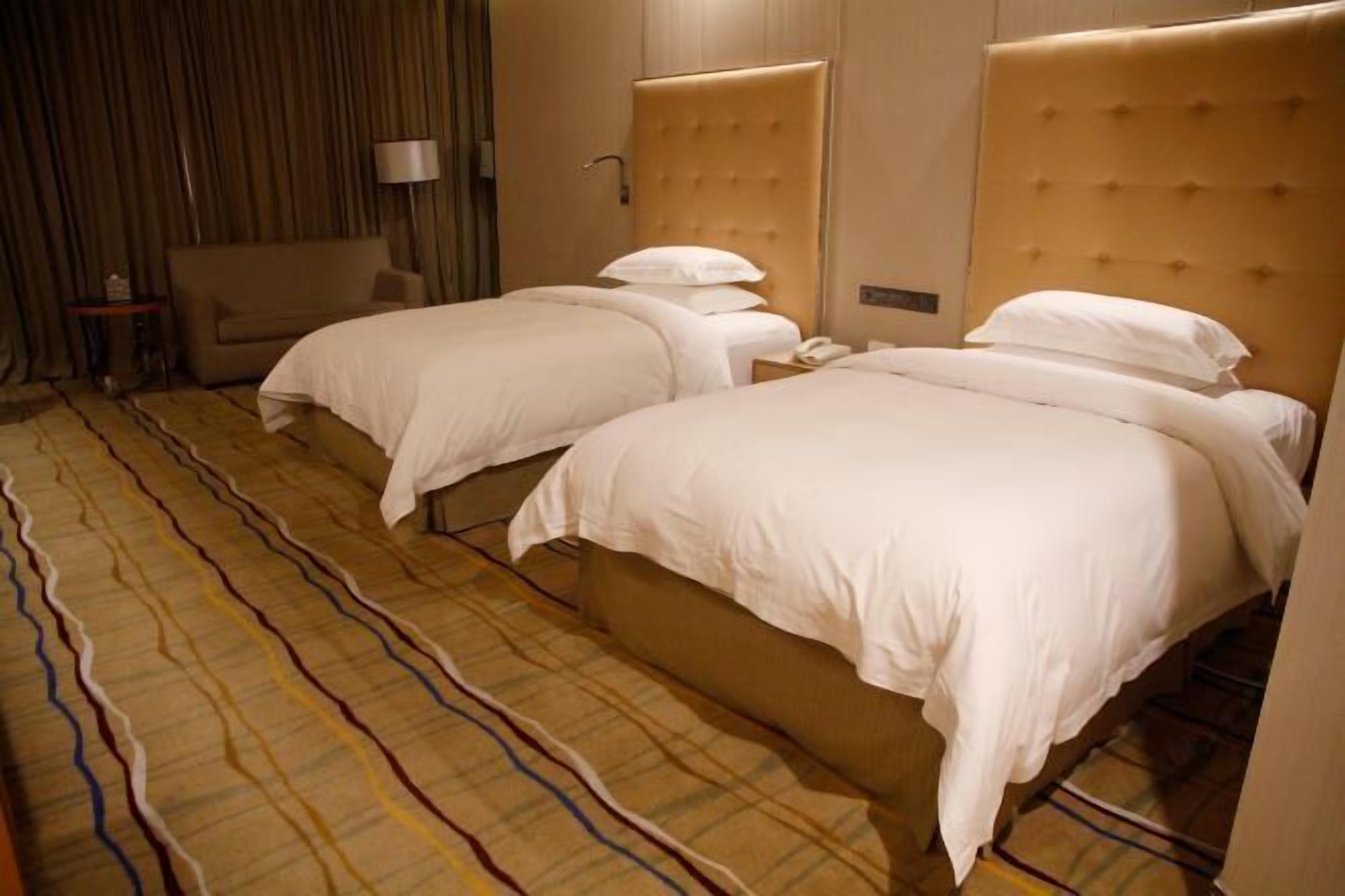 A hotel room with two beds, a sofa, and a patterned carpet.
