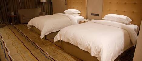 A hotel room with two beds, a sofa, and a patterned carpet.