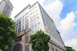 Um edifício com vários andares, grandes janelas e uma entrada em arco imponente.