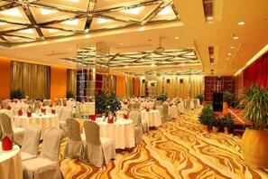 Un salón de banquetes con mesas redondas, sillas y una alfombra estampada.