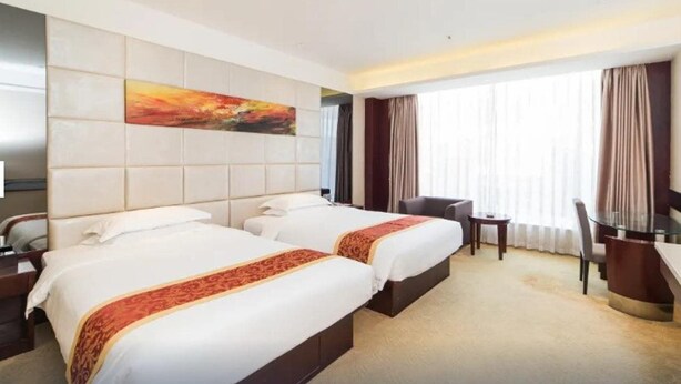 A hotel room with two beds, a desk, a chair, and a large window with curtains. - Haili Business Hotel - Zhuhai (ZHUHAI)