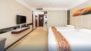 A hotel room with a large bed, a flat-screen TV, a bedside table, and a painting on the wall. - Haili Business Hotel - Zhuhai (ZHUHAI)