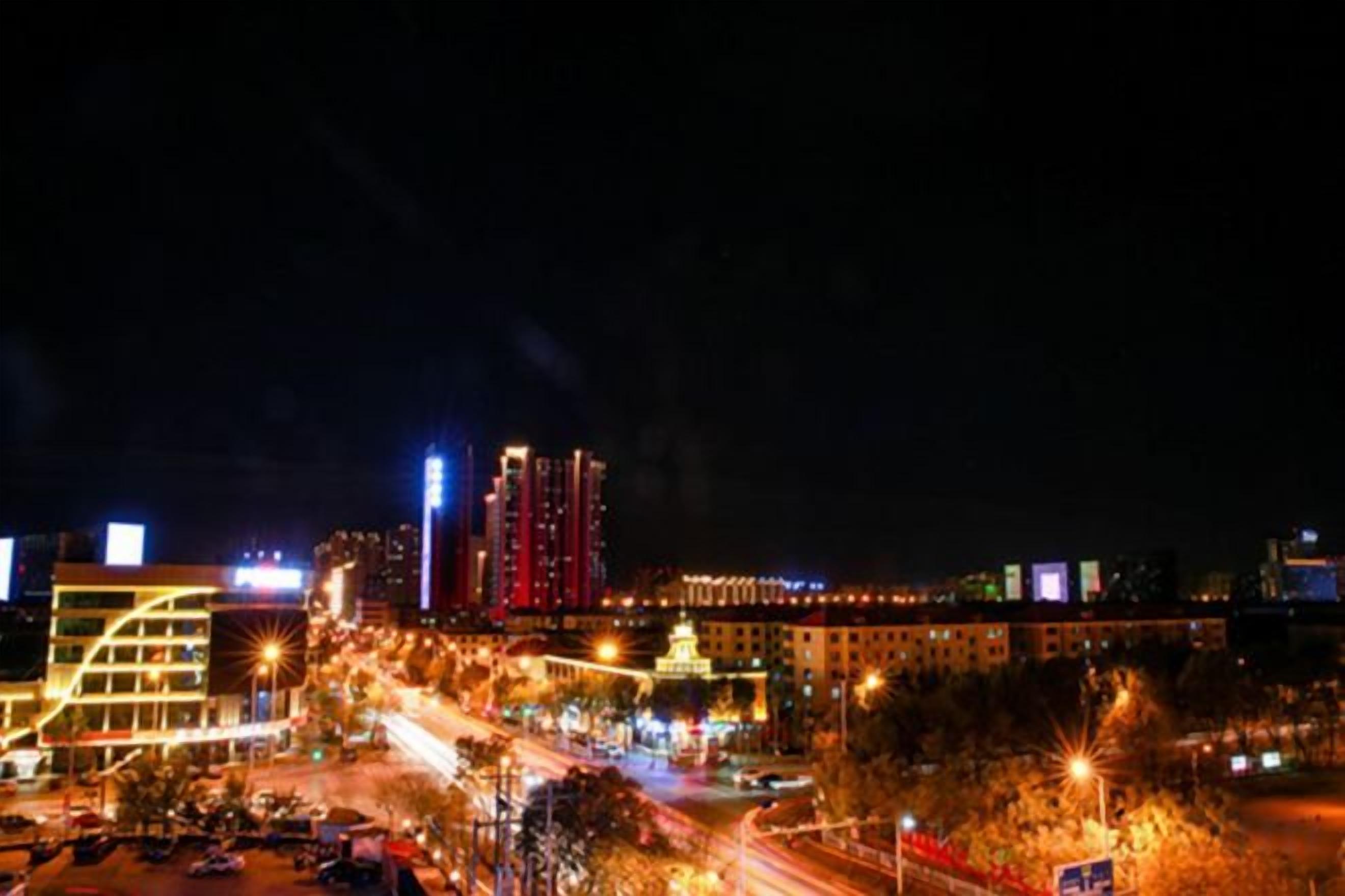 A nighttime cityscape with illuminated buildings and a busy street.