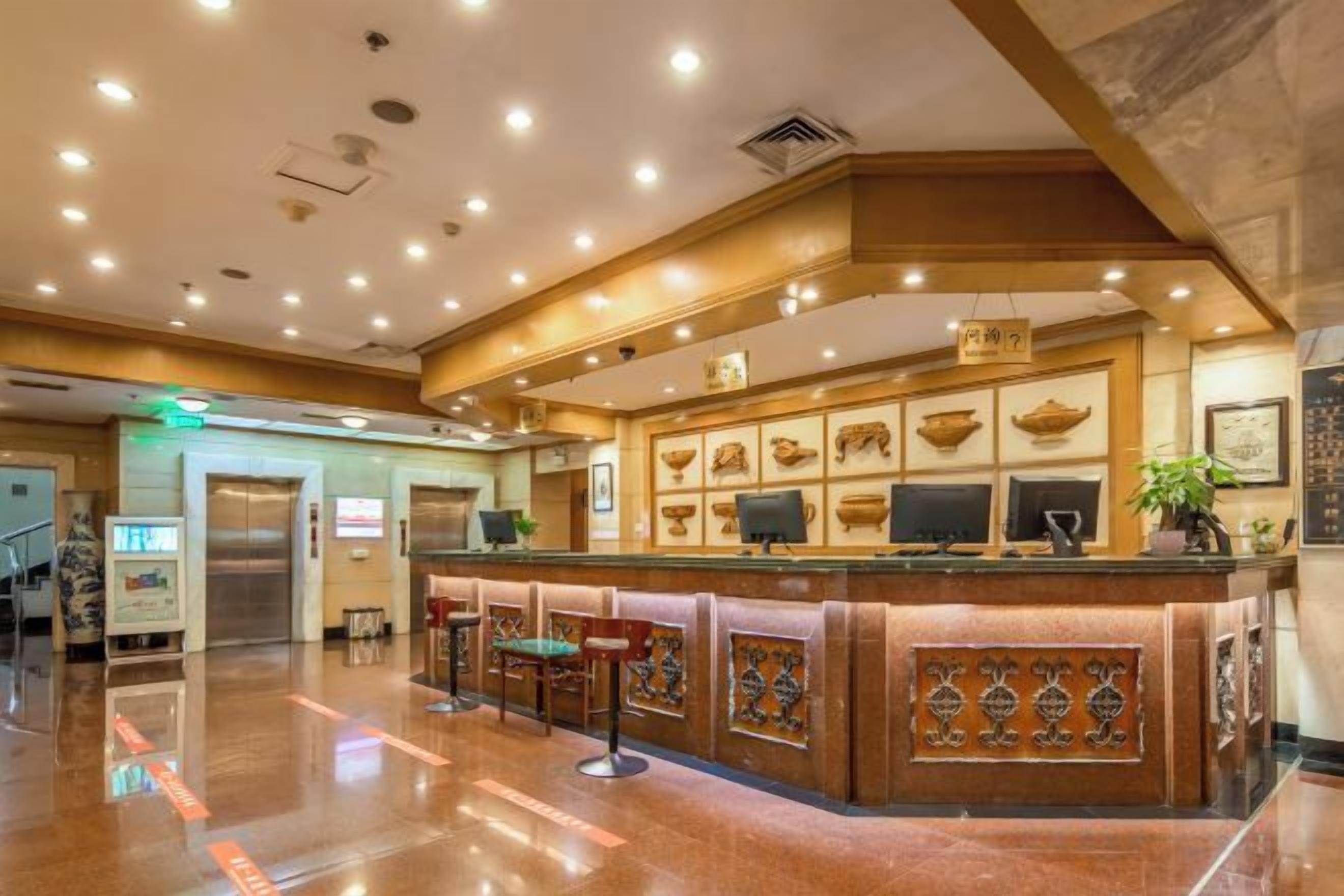 A hotel lobby with a reception desk, seating area, and a staircase.