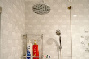 A shower with a handheld showerhead, a wall-mounted faucet, and a shelf with toiletries. - Jinsui Hotel (Hohhot)
