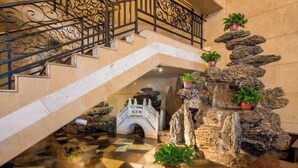 A hotel lobby with a stone waterfall feature, a decorative bridge, and potted plants. - Jinsui Hotel (Hohhot)