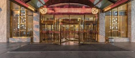 A hotel entrance with a revolving door, marble walls, and a modern design.