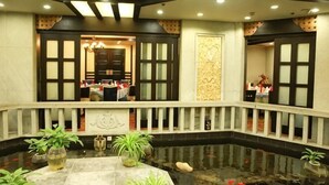 A hotel lobby with a central water feature, a reception desk, and a decorative wall. - Jinsui Hotel (Hohhot)