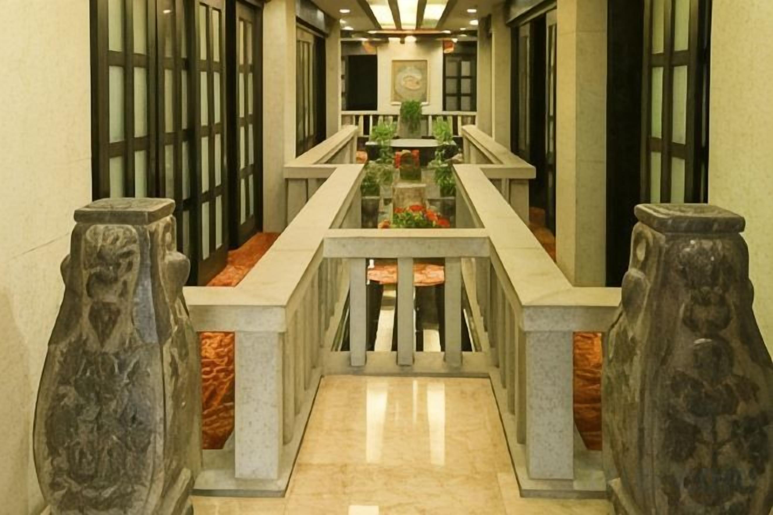 A corridor with a marble floor, stone balustrades, and a central railing.
