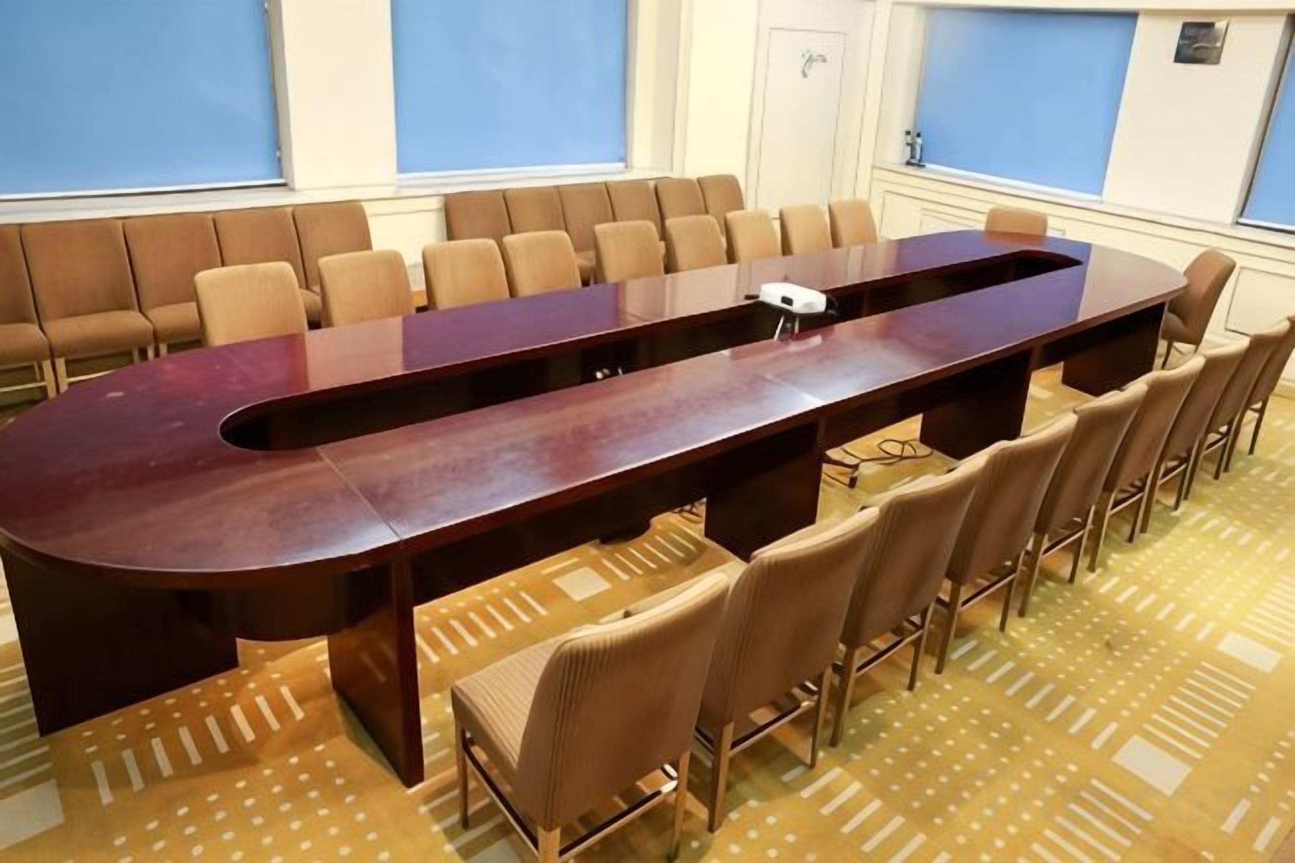 Ett konferensrum med ett långt bord, stolar och en mönstrad matta.