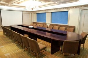 A conference room with a long table, multiple chairs, and a projector screen. - Jinsui Hotel (Hohhot)