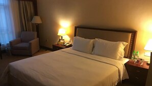 A hotel room with a large bed, two bedside tables, a chair, and a lamp. - Borrman Hotel Dongguan Changping Avenue (Dongguan)