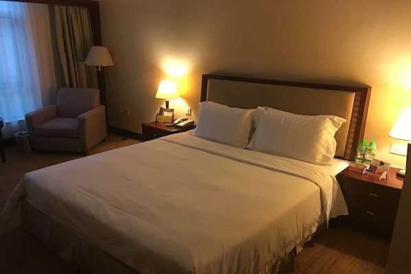 A hotel room with a large bed, two bedside tables, a chair, and a lamp. - Borrman Hotel Dongguan Changping Avenue (Dongguan)