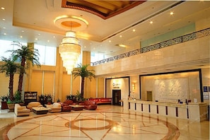 Un hall d’entrée spacieux, agrémenté d’un lustre central, de coins salon et d’un comptoir d’accueil.