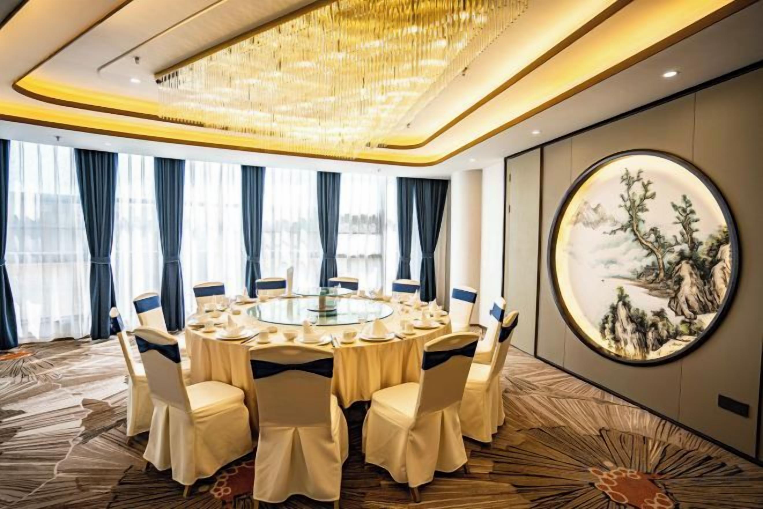 Une salle de conférence avec une table ronde, des chaises et un lustre.