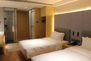Quarto de hotel com duas camas, mesa de cabeceira com telefone e área de chuveiro.