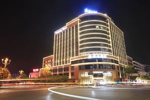 Um hotel de vários andares com fachada curva, sinalização iluminada e entrada destacada.