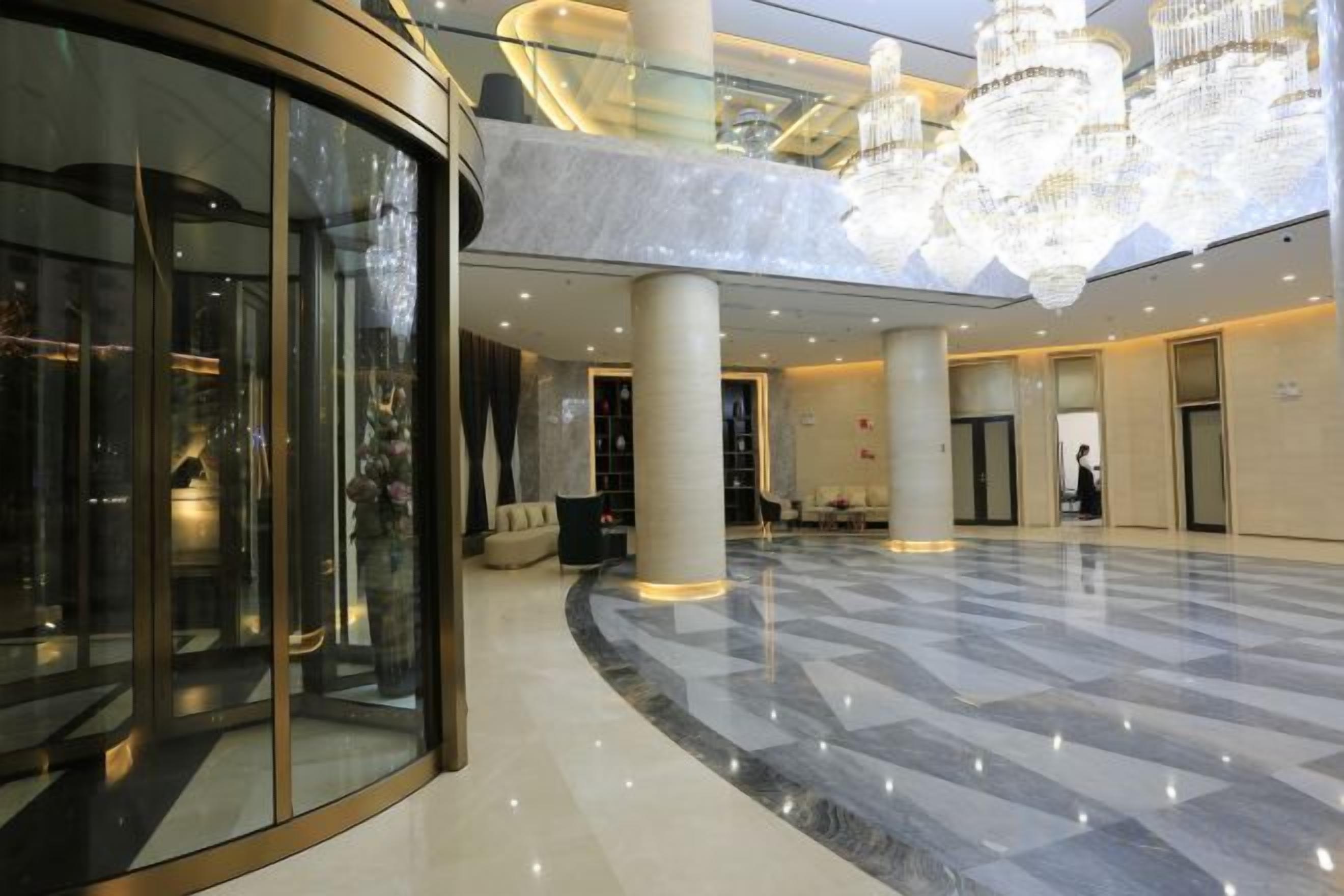 A spacious lobby with a marble floor, large glass doors, and a chandelier.