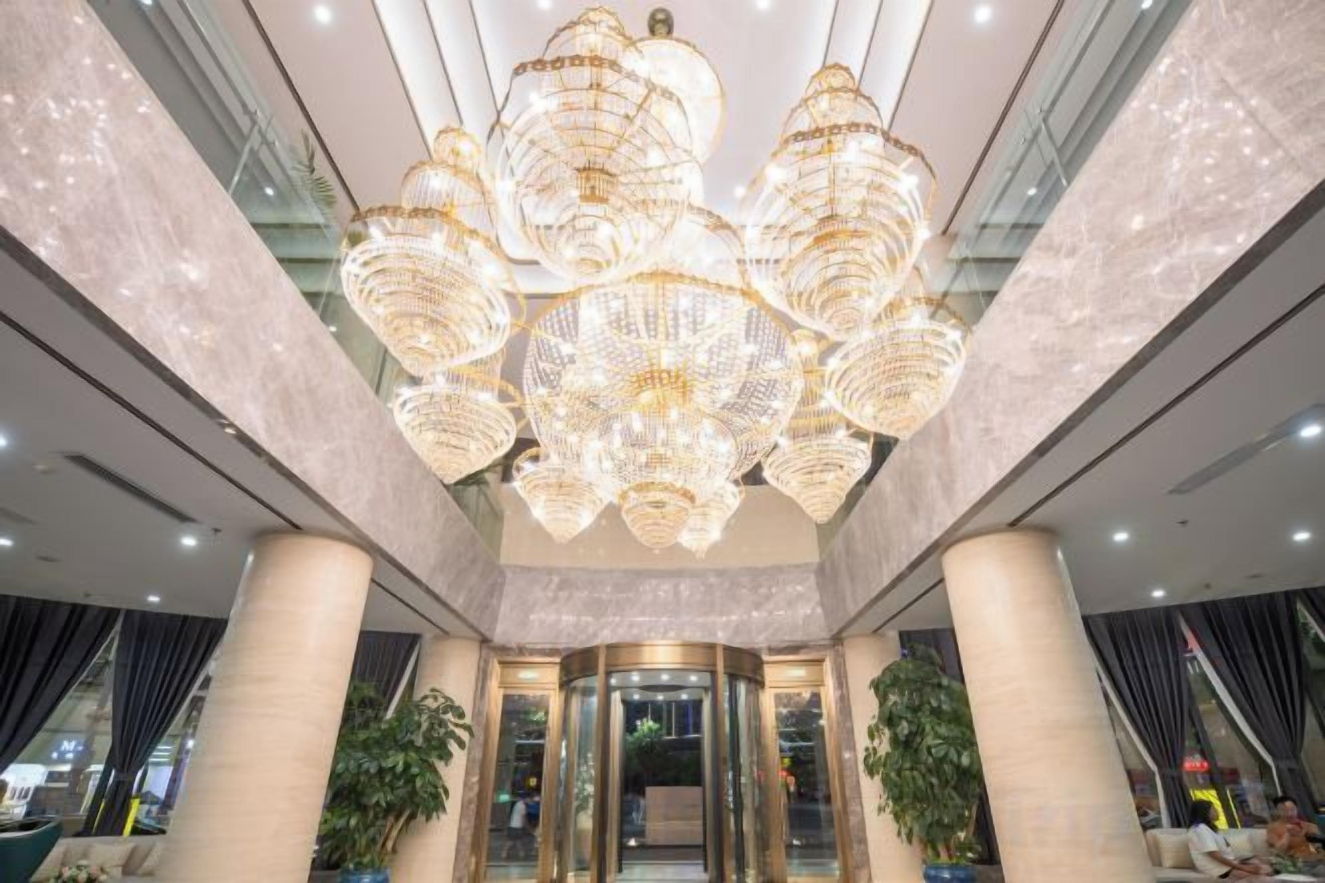 A lobby with a large chandelier, marble columns, and a glass entrance.