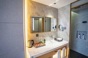 Une salle de bain moderne avec un meuble-lavabo en marbre, un grand miroir, un espace douche et un porte-serviettes.
