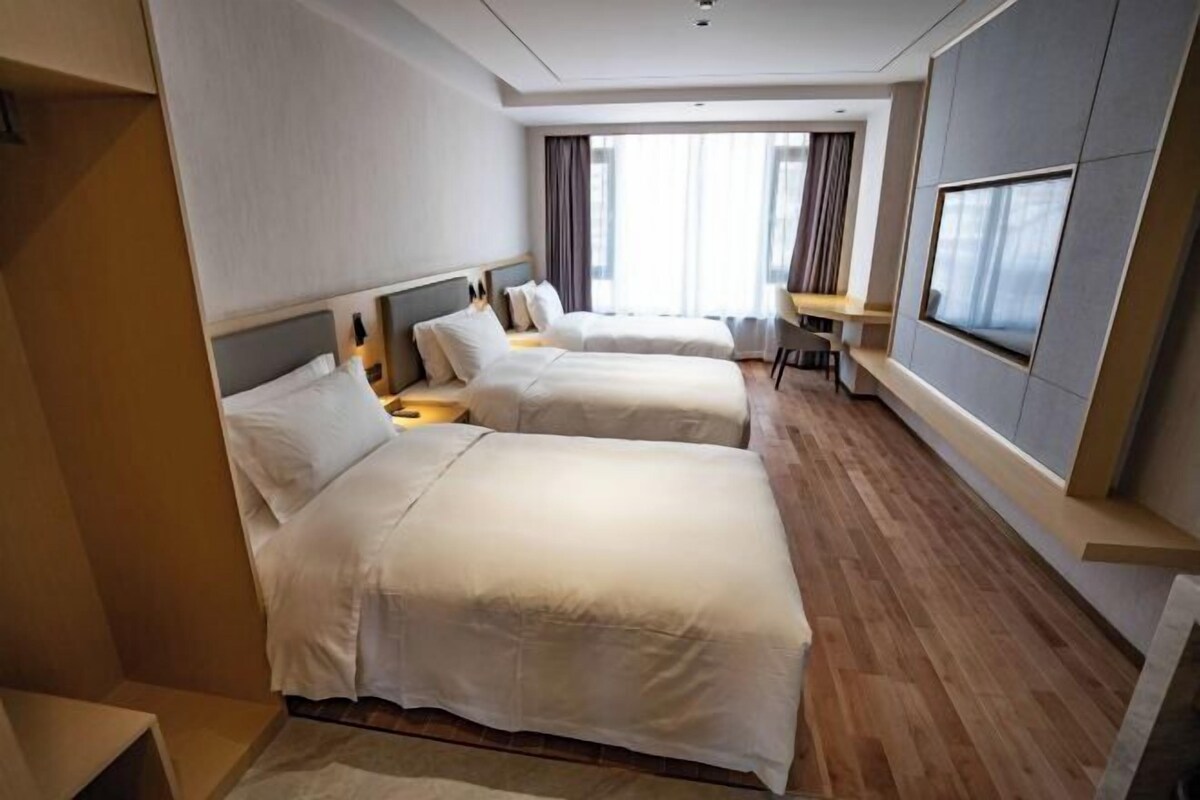 Une chambre d’hôtel avec deux lits, un bureau et une grande fenêtre.