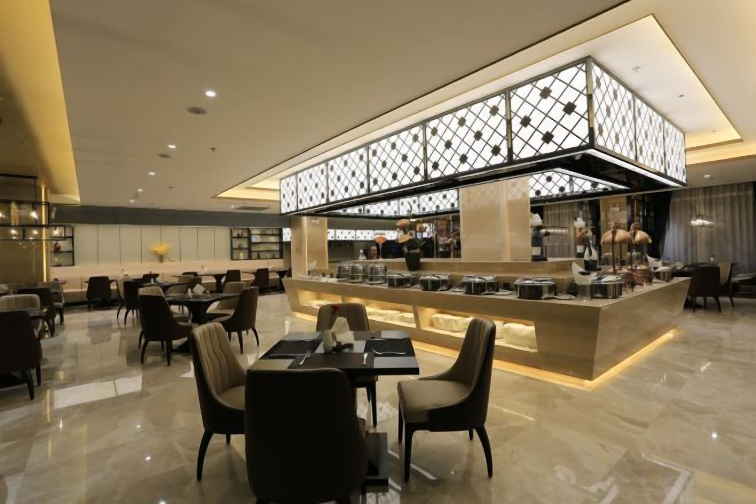 Un restaurante moderno con barra central, disposición de mesas y techo decorativo.