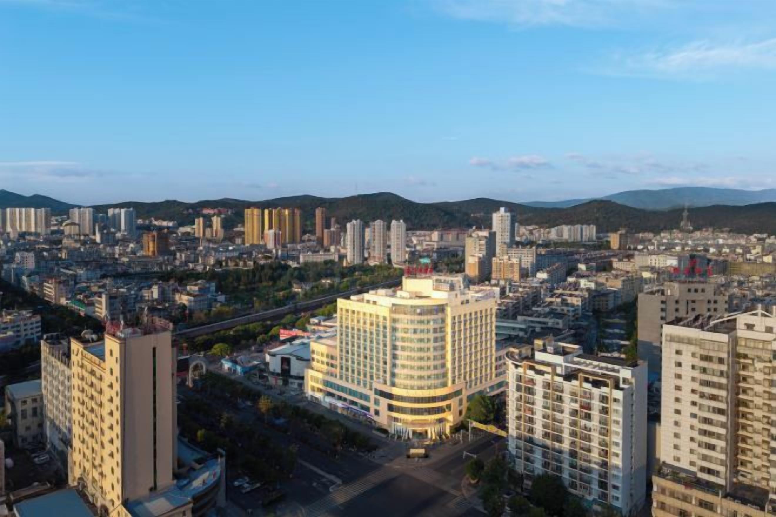 A cityscape with high-rise buildings, a prominent white building with a curved facade, and a clear sky.