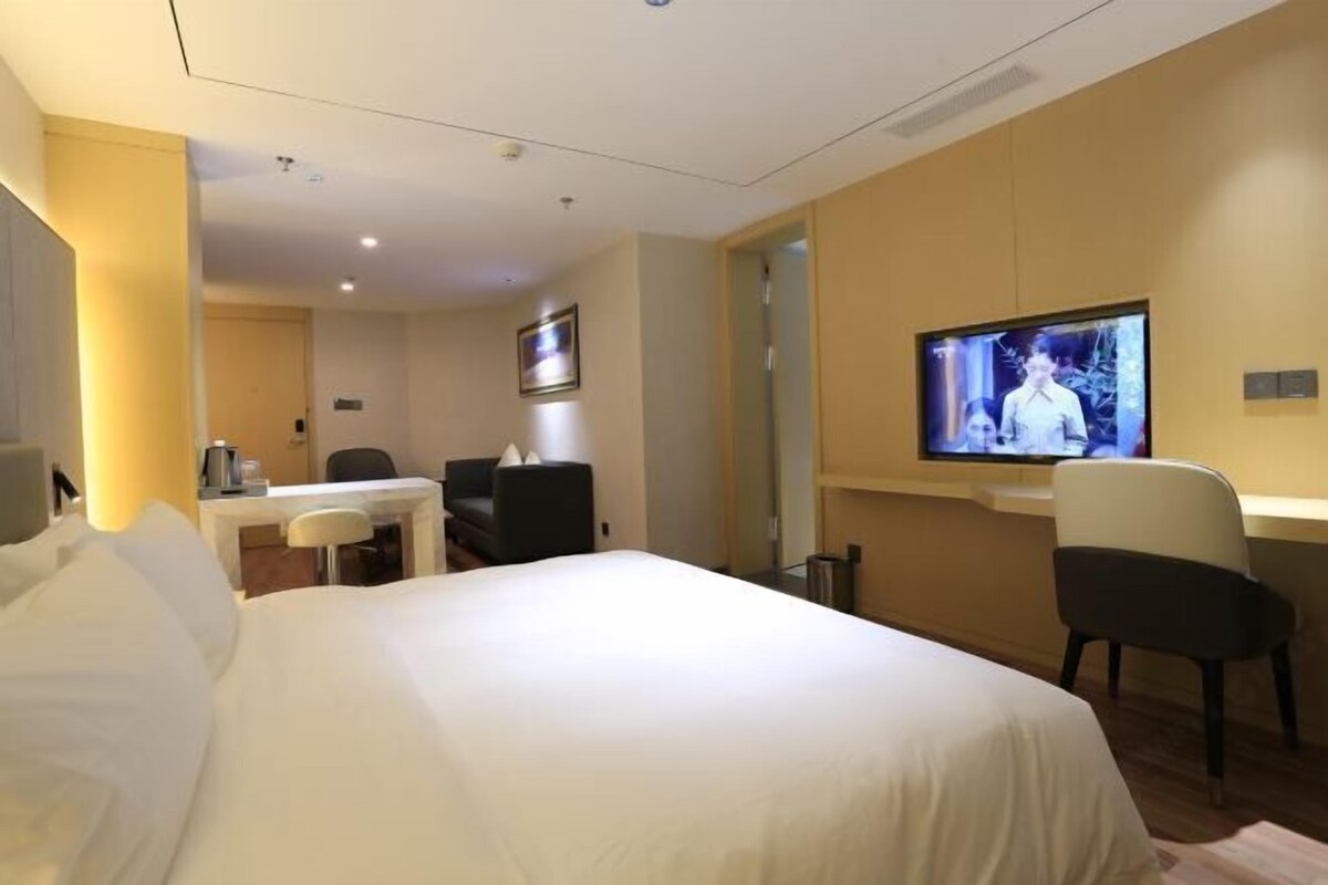 Une chambre d’hôtel équipée d’un lit, d’un bureau, d’une chaise, d’une télévision et d’une petite table sur laquelle se trouve une machine à café.