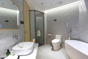 Une salle de bain moderne avec une baignoire sur pieds, des toilettes et un grand miroir.