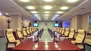 A conference room with a long table, multiple chairs, and a television screen on the wall. - Uiles Hotel (Hohhot)