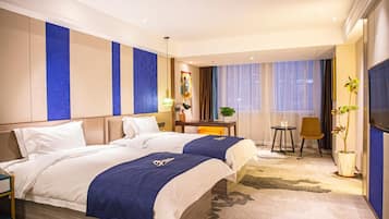 Ein Hotelzimmer mit Bett, Schreibtisch, Stuhl, Fernseher und Pflanze.