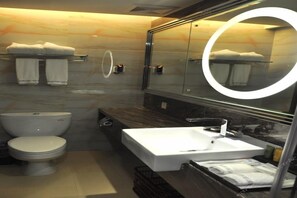 A modern bathroom with a toilet, sink, and mirror. - Foshan Shunde Austin Baili Apartment (Foshan)