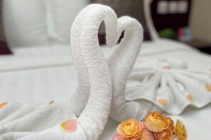 A bed with a white bedspread and two swan-shaped pillows. - Golden Palace Hotel (Kunming)